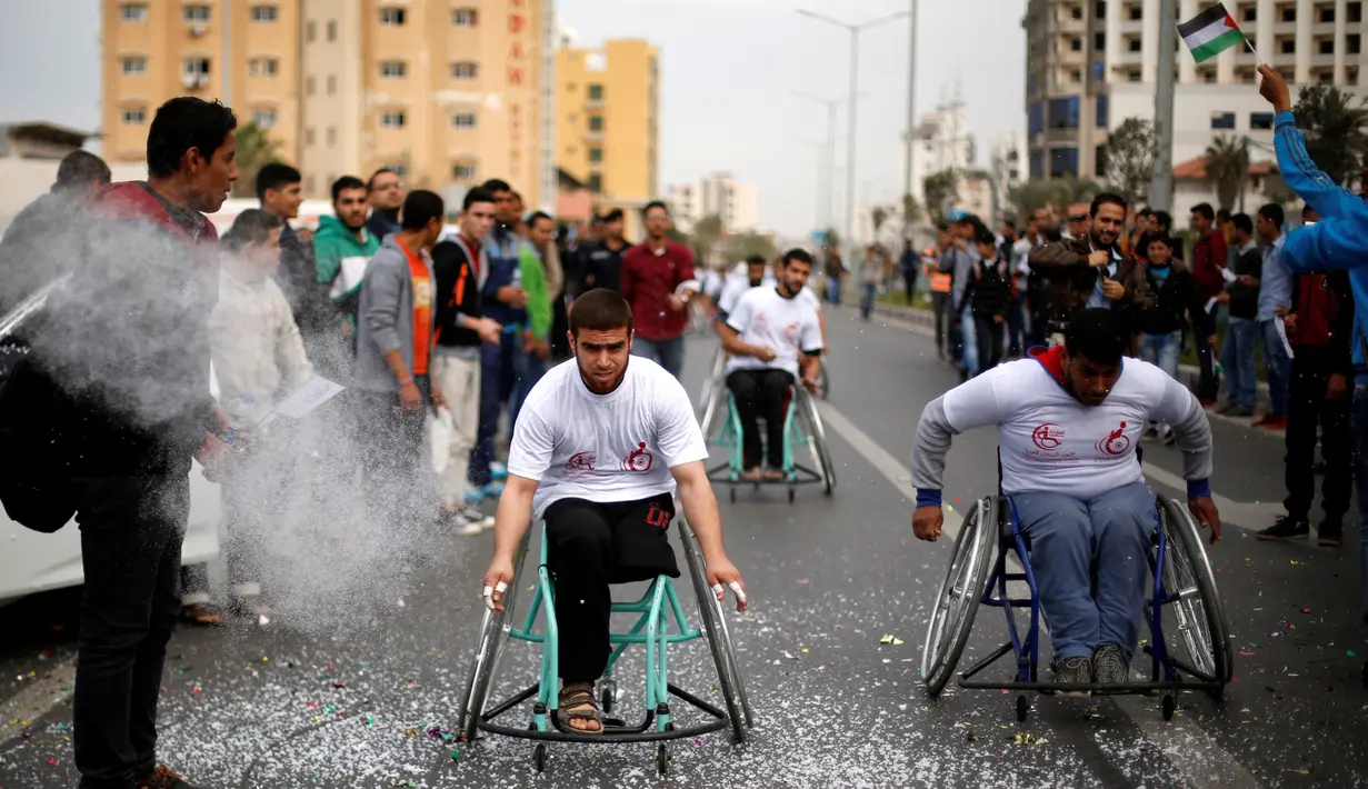 Para peserta saat bersaing mencapai garis finis dalam perlombaan kursi roda di Kota Gaza, (29/11). Lomba ini diselenggarakan untuk para warga yang mengalami cacat fisik akibat konflik sejak tahun 2008 dengan militer Israel. (REUTERS/Suhaib Salem)