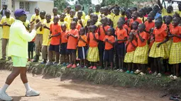 Rapper AS, Kanye West bertepuk tangan sambil bernyanyi bersama anak-anak dalam kunjungannya ke Kampung Anak UWESCO di Masulita, Uganda, Selasa (16/10). Ditemani Kim Kardashian, Kanye West berada di Uganda untuk misi kemanusiaan. (AP/Stephen Wandera)