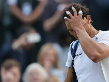 Petenis Spanyol, Rafael Nadal, mengusap rambutnya sambil meninggalkan lapangan setelah dikalahkan Giller Muller (Luksemburg) di perempat final Wimbledon 2017, Senin (10/7). Nadal menyerah dari Mueller usai melewati pertarungan lima set. (AP/Tim Ireland)
