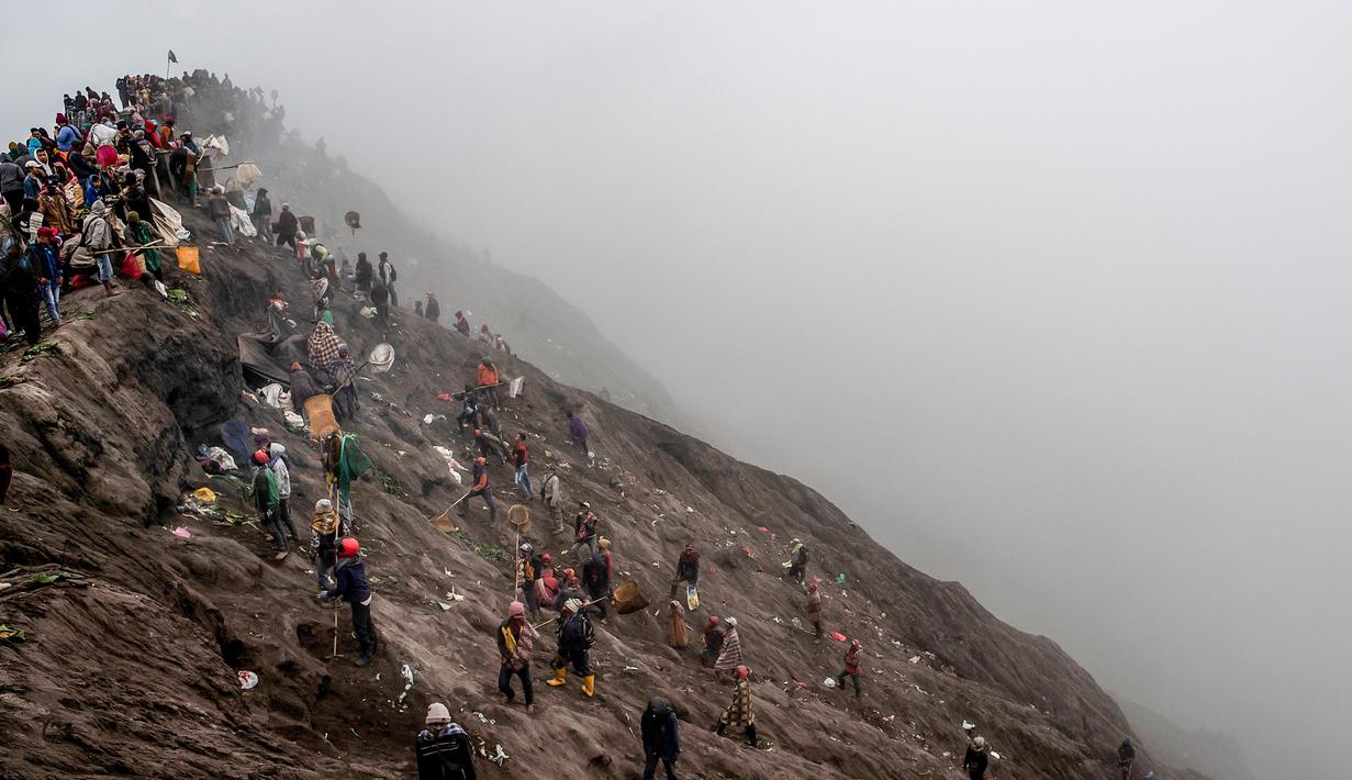 Sejumlah orang mencoba menangkap sajen yang dilemparkan ke kawah dalam ritual Yadnya Kasada di Gunung Bromo, Probolinggo, Jawa Timur, Kamis (18/7/2019). Ritual yang selalu berlangsung pada saat bulan purnama ini sudah dilangsungkan sejak abad ke-14. (JUNI KRISWANTO/AFP)