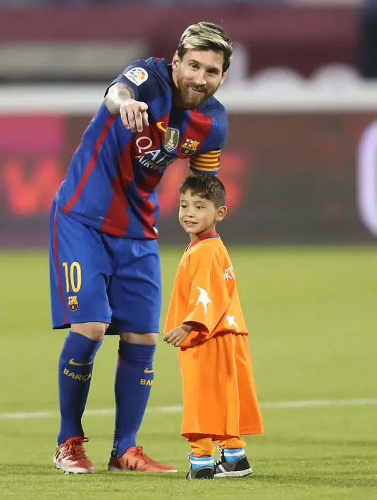 Bintang Barcelona Lionel Messi dan bocah Afghanistan, Murtaza Ahmadi berbincang jelang laga melawan Al Ahli di Doha, Qatar, Selasa (13/12). Murtaza menjadi sensasi di internet karena mengenakan plastik bernomor punggung 10 untuk Messi. (Karim Jaafar/AFP)