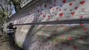 Anggota keluarga yang berduka melukis hati di Dinding Peringatan COVID-19 di seberang Gedung Parlemen Inggris, di London, Senin (29/3/2021). Mural hampir 150.000 lukisan hati tersebut untuk mengenang ribuan orang yang telah meninggal akibat virus corona di Inggris. (AP Photo/Kirsty Wigglesworth)