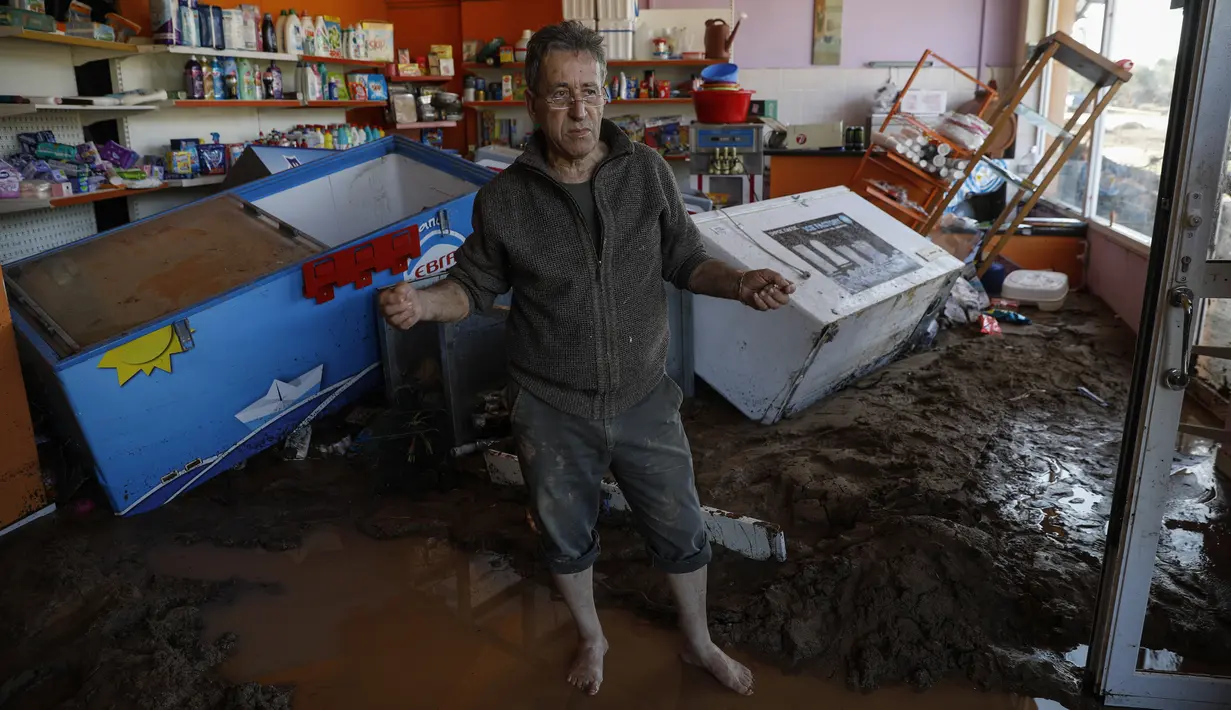 Seorang pria berdiri di dalam tokonya yang hancur setelah badai di desa Kineta, Athena (25/11/2019). Ratusan rumah terendam banjir setelah badai semalam menerjang daerah barat Athena. (AP Photo/Petros Giannakouris)