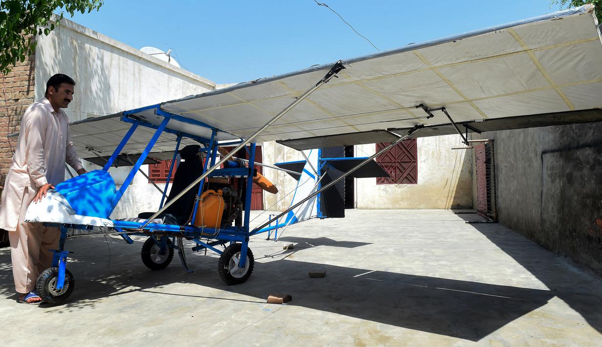 Muhammad Fayyaz berdiri di samping pesawat buatannya di Desa Tabur, Provinsi Punjab, Pakistan, 8 April 2019. Pangkalan Udara Pakistan terdekat mengeluarkannya sertifikat untuk menghargai semangat dan ketangkasan Fayyaz. (ARIF ALI/AFP)
