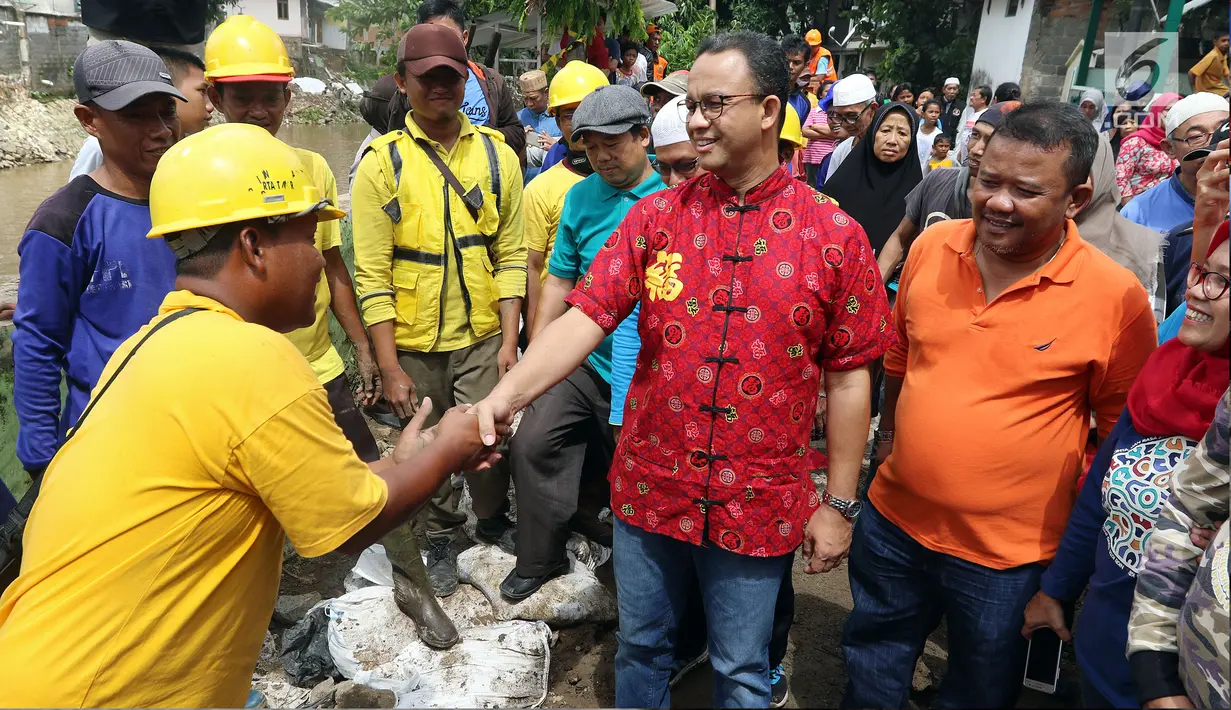 Gubernur DKI Anies Baswesdan berbincang dengan petugas saat meninjau lokasi jalan retak di Kelurahan Kebon Manggis, Kecamatan Matraman, Jakarta Timur, Jumat (16/2). Anies melihat upaya petugas melakukan perbaikan jalan tersebut. (Liputan6.com/Johan Tallo)