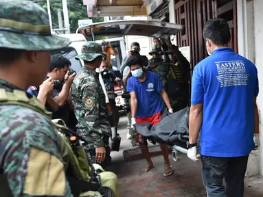 Personel polisi Filipina mengamati pekerja yang membawa jasad seorang napi yang tewas akibat kerusuhan di sebuah penjara di Filipina, Rabu (28/9). Selain menewaskan satu anggota geng narkoba, kerusuhan itu juga melukai tiga napi lainnya. (TED Aljibe/AFP)