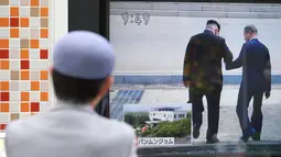 Seorang pria di Tokyo menonton TV yang memperlihatkan berita saat Pemimpin Korea Utara, Kim Jong-un mengajak Presiden Korea Selatan, Moon Jae-in melintasi perbatasan Zona Demiliterisasi (DMZ) ke wilayah Korea Utara, Jumat (27/4). (AP/Eugene Hoshiko)