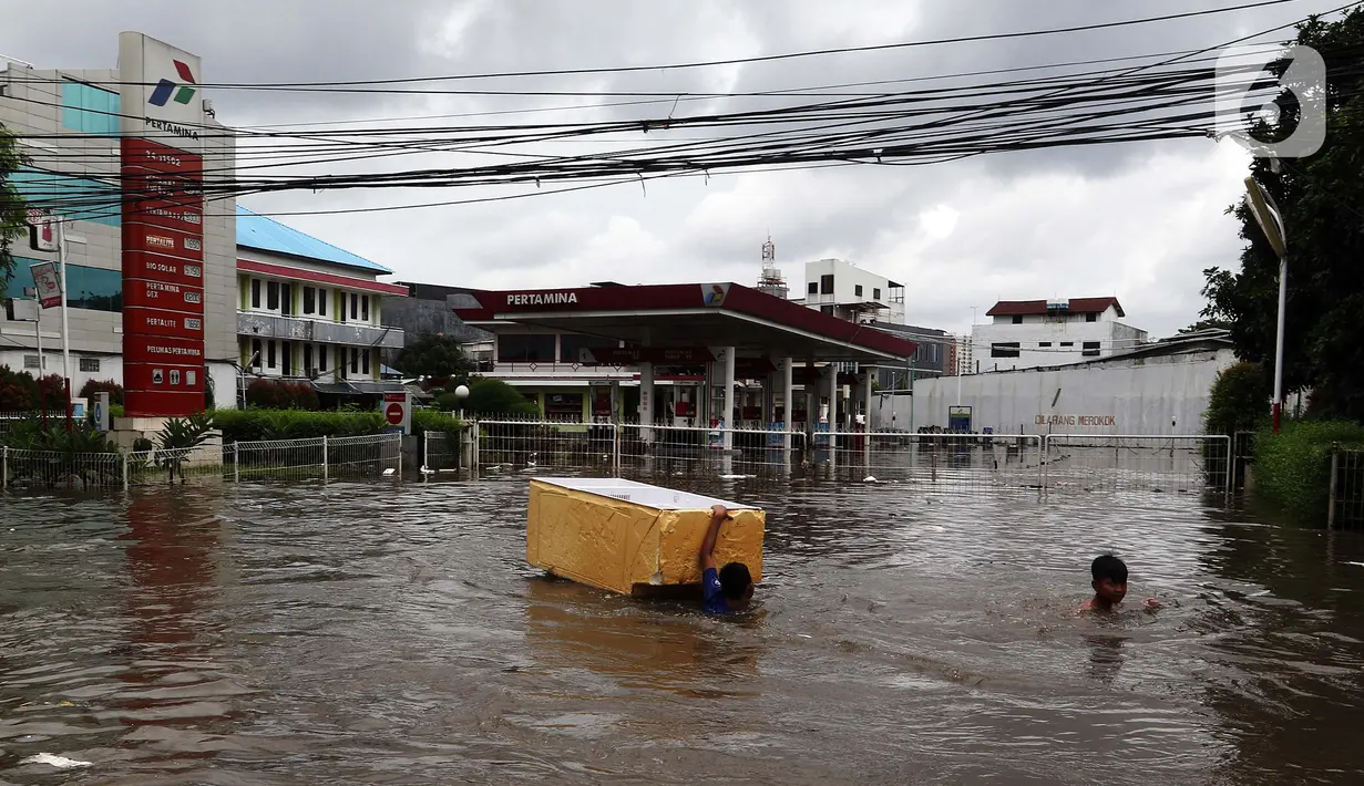 Dua orang anak bermain banjir yang merendam kawasan Green Garden, Jakarta Barat, Selasa (25/2/2020). Hujan yang mengguyur kawasan Jakarta membuat kawasan tersebut tergenang banjir setinggi 60-80 cm. (Liputan6.com/Johan Tallo)