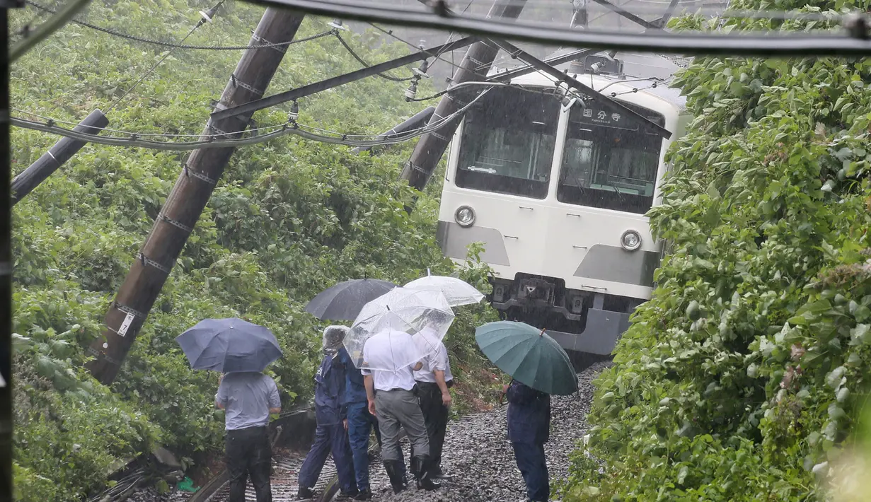 Petugas mengamati kereta yang tergelincir dalam tanah longsor yang disebabkan topan mindulle di Higashimurayama, Tokyo, Senin (22/8). Ratusan penerbangan serta perjalanan kereta api di Tokyo dibatalkan akibat terjangan Topan Mindulle. (Jiji Press/AFP)