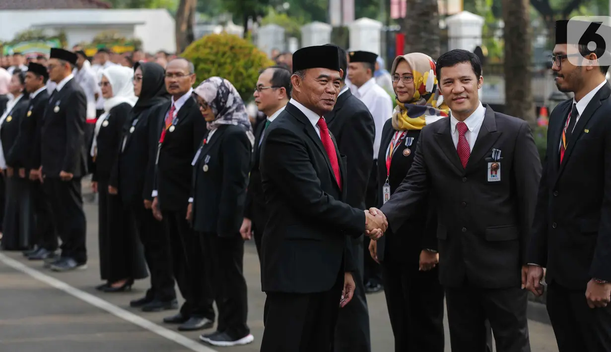Menko PMK Muhadjir Effendy memberikan selamat usai menyematkan tanda kehormatan Bintang Satyalancana Karya Satya kepada sejumlah PNS saat memimpin upacara peringatan Sumpah Pemuda di kantor Kemenko PMK, Jakarta, Senin (28/10/2019). (Liputan6.com/Faizal Fanani)