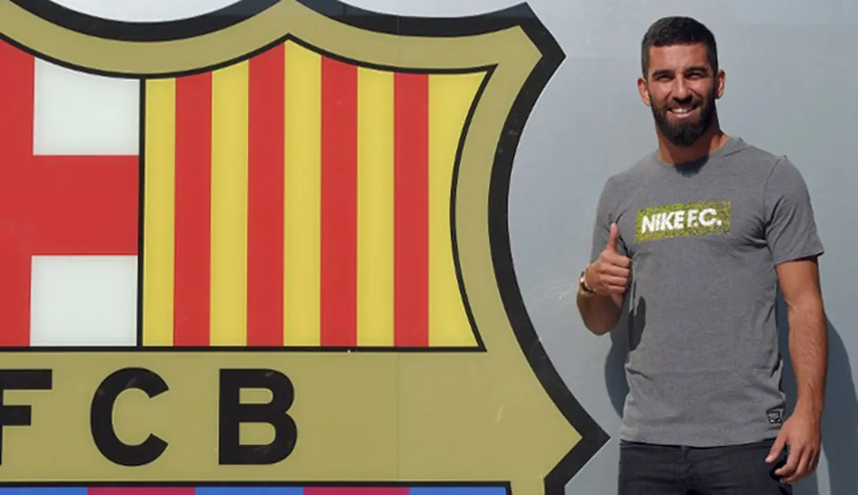 Arda Turan mengacukan ibu jari ke awak media saat sesi perkenalan di luar Stadion Camp Nou, Barcelona, Spanyol, (9/7/2015). Pemain kelahiran 30 Januari 1987 resmi di kontrak  Barcelona hingga lima tahun ke depan. (AFP PHOTO/Lluis GENE)