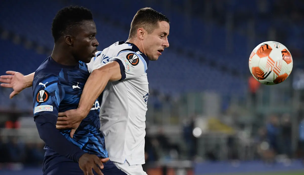 Penyerang Olympique Marseille, Bamba Dieng (kiri) berebut bola dengan bek Lazio Adam Marusic pada matchday kedua Grup E Liga Europa 2021 di Stadion Olimpico Roma, Kamis (21/10/2021) malam WIB. Lazio hanya mampu bermain imbang 0-0 kala menjamu Marseille. (Filippo MONTEFORTE / AFP)