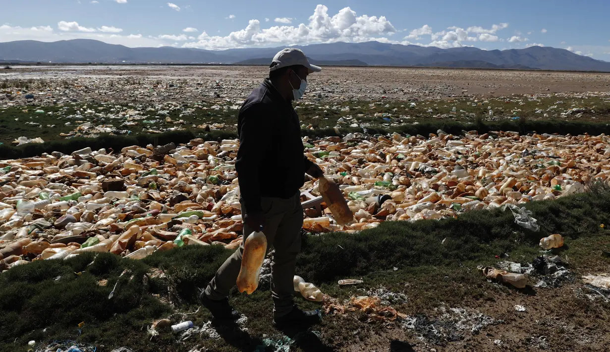 Limbert Sanchez, anggota Pusat Ekologi dan Masyarakat Andes, membawa botol yang diambil dari lautan sampah yang memenuhi Sungai Tagaret, Bolivia, yang kering, Kamis (25/3/2021). Sungai ini mengalir ke Danau Uru Uru dengan membawa sampah-sampah yang mencemari danau. (AP Photo / Juan Karita)