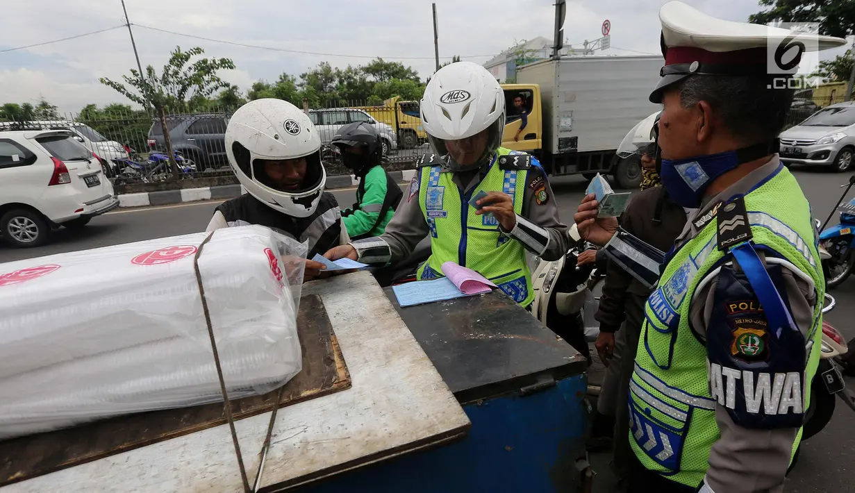 Petugas kepolisian memberi surat tilang ke pengendara saat Operasi Zebra Jaya 2017 di Daan Mogot, Jakarta, Selasa (7/11). Operasi Zebra yang digelar 1 November- 14 Desember 2017 tersebut secara serentak dilakukan se-Indonesia. (Liputan6.com/Johan Tallo)
