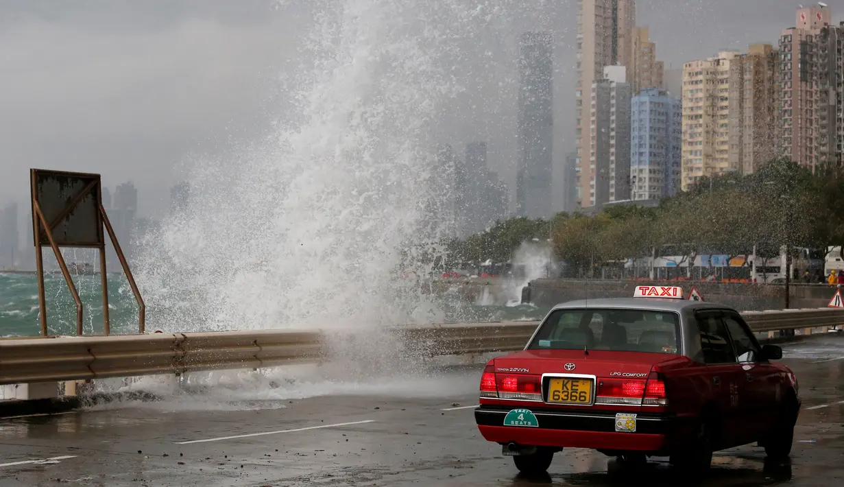 Sebuah taksi melintas di dekat ombak besar yang menghantam pesisir Hong Kong, Tiongkok, Jumat (21/10). Akibat terjangan angin berkecepatan 160 kilometer per jam itu, sedikitnya 700 penerbangan di Hongkong ditunda atau dibatalkan. (REUTERS/Bobby Yip)