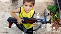 Seorang bocah Azaz bermain dengan senapan AK-47 milik ayahnya beberapa km 47 (29 mil) Utara Aleppo. (Reuters/Goran Tomasevic/wwn)