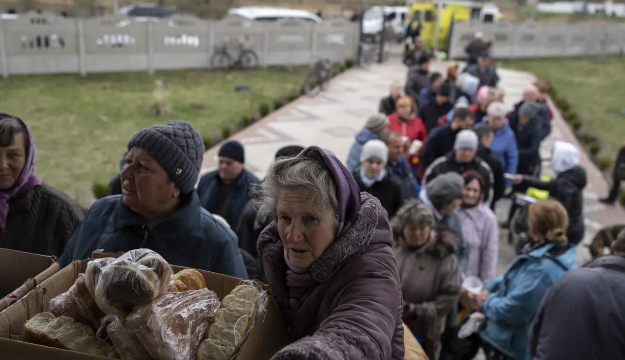 Orang-orang menerima makanan dari sebuah gereja di kota Borodyanka, sekitar 40 mil barat laut Kiev, Ukraina, pada hari Minggu, 10 April 2022. Invasi Rusia ke Ukraina hingga saat ini telah berlangsung selama 46 hari. (AP Photo/Petros Giannacouris)