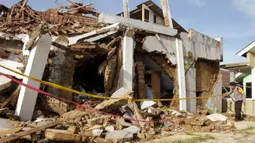 Seorang polisi memeriksa rumah yang runtuh gempa magnitudo 5,1  di Sukabumi, Jawa Barat (10/3/2020). Hasil analisis mekanisme sumber menunjukkan bahwa gempabumi memiliki mekanisme pergerakan mendatar (Strike-Slip Fault). (AFP/Wulung Widarba)
