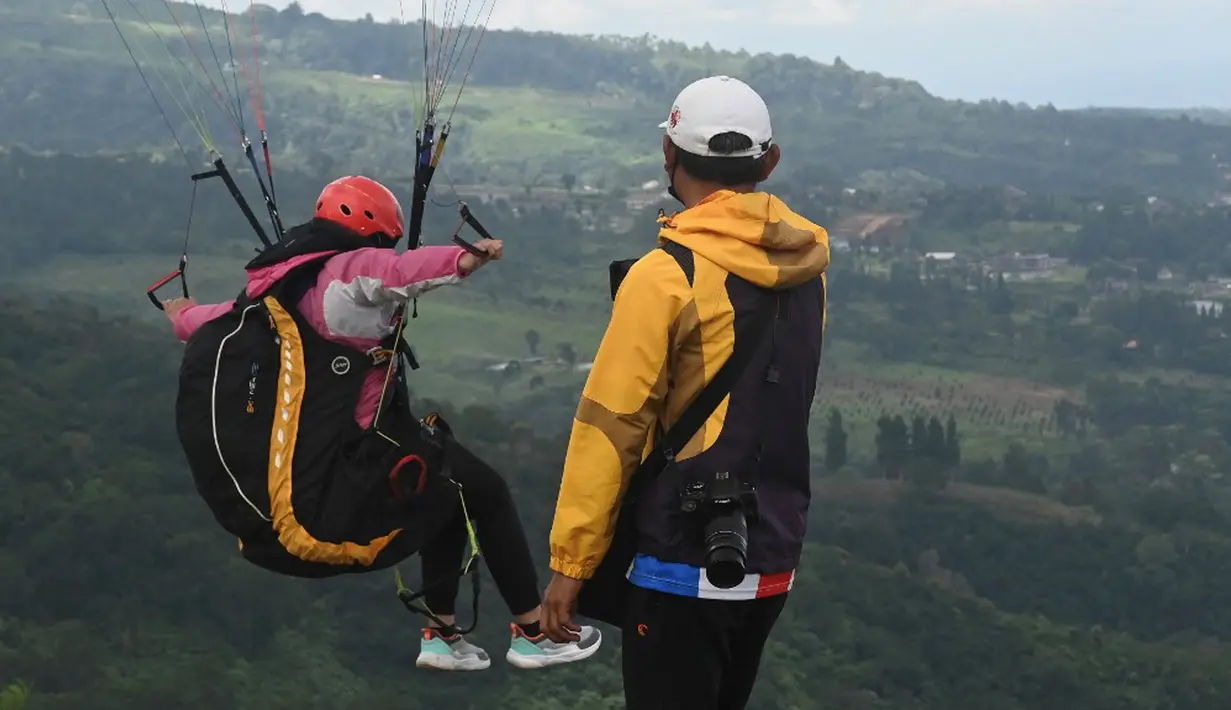 Seorang paraglider lepas landas dari lereng bukit di Puncak, Bogor, Jawa Barat, Kamis (2/12/2021). Destinasi wisata alam Bukit Paralayang Puncak Bogor sangat cocok untuk dikunjungi pada liburan akhir pekan bersama keluarga, sahabat maupun pasangan tercinta. (Goh Chai Hin/AFP)