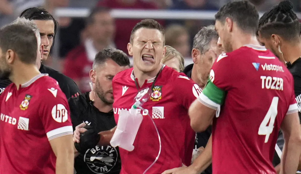 Pemain Wrexham, Paul Mullin dengan menggunakan alat bantu pernapasan dibantu sejumlah tim medis meninggalkan lapangan pertandingan setelah mengalami insiden dengan kiper Manchester United, Nathan Bishop pada laga uji coba pramusim di Snapdragon Stadium, San Diego, California, Rabu (25/07/2023) WIB. (AP Photo/Gregory Bull)
