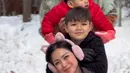 Jessica Iskandar mengenakan jaket hitam saat main salju bersama ketiga anaknya dan suaminya. Semakin cute dengan penutup telinga warna pink. [@inijedar]