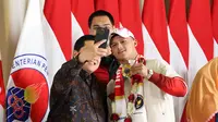 Rizki Juniansyah (kanan) berswafoto bersama Erick Thohir (depan kiri) dan Dito Ariotedjo saat penyambutan kedatangan kontingen Olimpiade di Bandara Internasional Soekarno-Hatta, Selasa (13/8/2024) malam WIB. (Bola.com/Abdul Aziz)