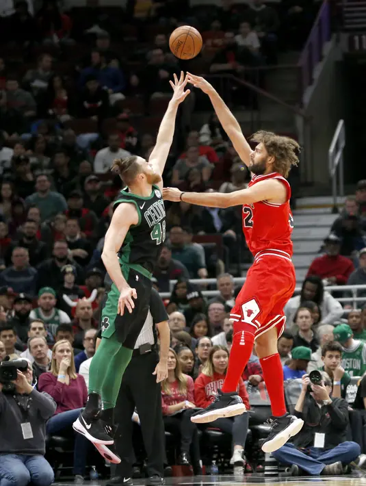 Pemain Chicago Bulls, Robin Lopez (kanan) melakukan tembakan melewati adangan pemain Boston Celtics, Aron Baynes pada lanjutan NBA basketball game di United Center, Chicago, (11/12/2017). Bulls menang 108-85. (AP/Charles Rex Arbogast)