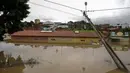 Tiang lampu miring terlihat saat banjir akibat hujan deras di Itapetinga, Negara Bagian Bahia, Brasil, 26 Desember 2021. Curah hujan bulan Desember di Ibu Kota Bahia, Salvador, mencapai 250 mm (milimeter) atau lima kali lebih tinggi dari rata-rata. (Manuella LUANA/AFP)