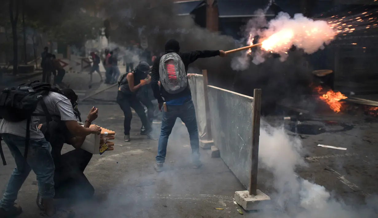 Sejumlah pengunjuk rasa melepaskan petasan ke arah polisi saat bentrokan memprotes rencana pembatasan belanja publik di Rio de Janeiro, Brasil, (9/2). (AP Photo/Felipe Dana)