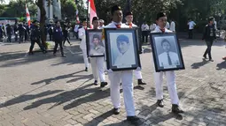 Mahasiswa berjalan sambil memegang foto aktivis yang tewas saat menggelar aksi peringatan 'Tragedi Trisakti 12 Mei 1998' di Universitas Trisakti, Jakarta, Selasa (12/5/2015). (Liputan6.com/Johan Tallo)
