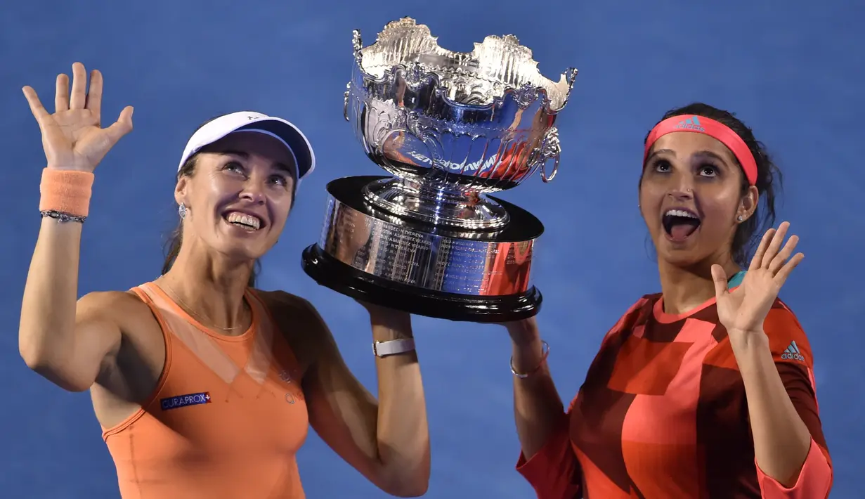 Martina Hingis (kiri) dan Sania Mirza berpose dengan trofi juara ganda putri setelah mengalahkan Lucie Hradecka dan Andrea Hlavackova di final tenis Australia Terbuka 2016 di Melbourne Park, Australia, (29/1/2016). (AFP/Peter Parks)