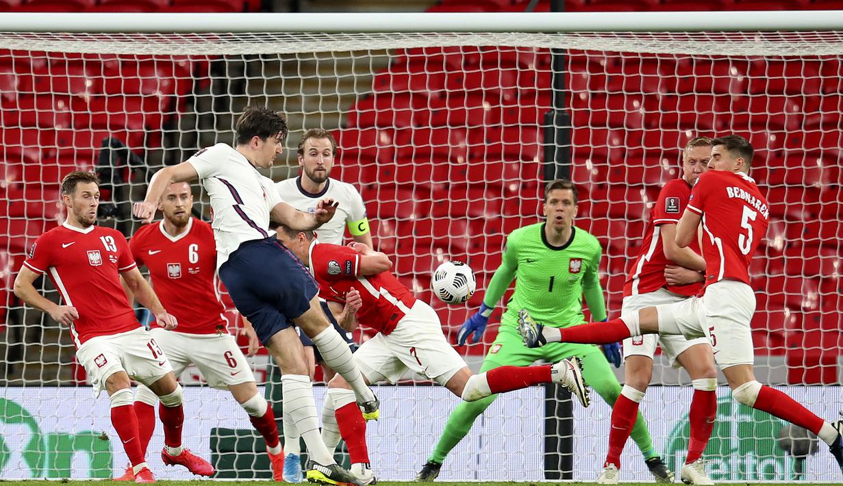 Bek Inggris, Harry Maguire (tengah) melepaskan tendangan yang berbuah gol kedua Inggris ke gawang Polandia dalam laga lanjutan Kualifikasi Piala Dunia 2022 Zona Eropa Grup I di Wembley Stadium, London, Rabu (31/3/2021). Inggris menang 2-1 atas Polandia. (AP/Andy Rain)