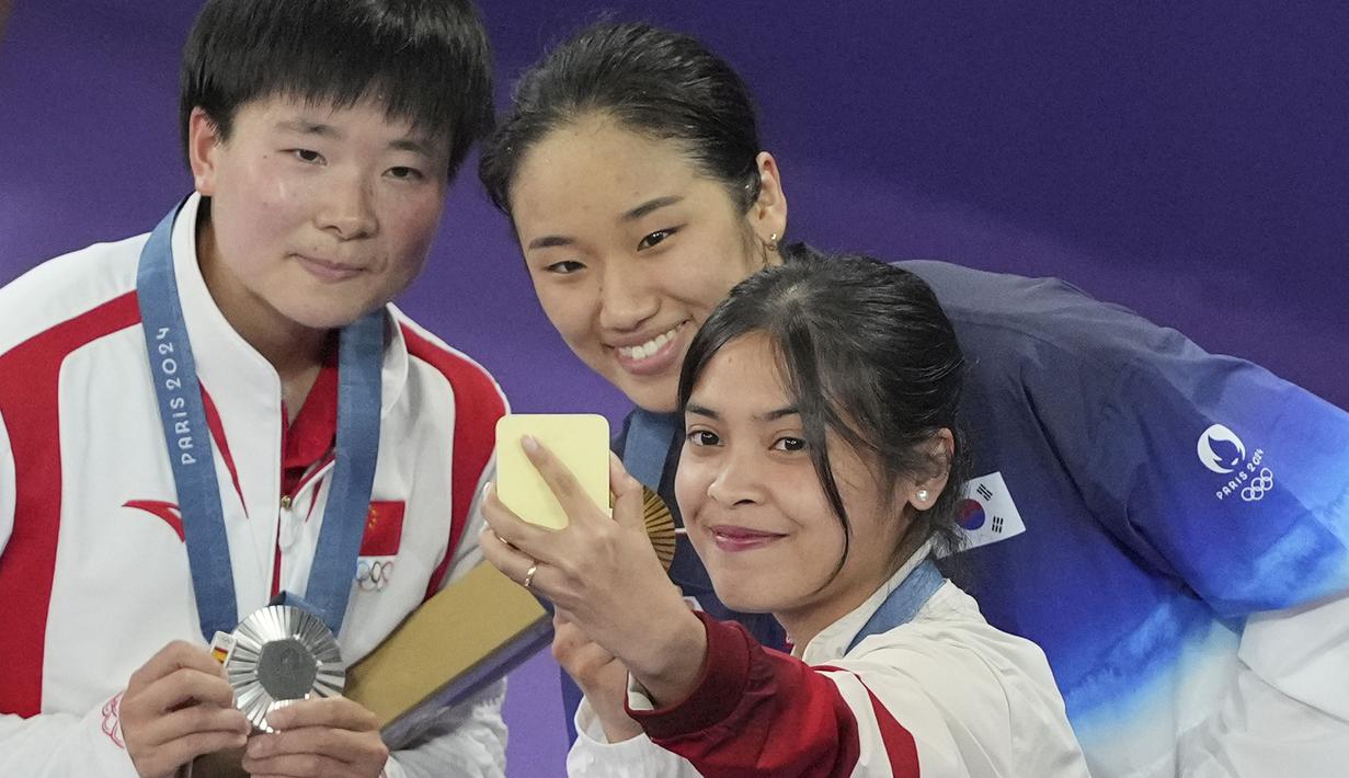 (Dari kanan) pebulu tangkis Indonesia peraih medali perunggu, Gregoria Mariska Tunjung, peraih medali emas An Se-young (Korea Selatan) dan peraih medali perak He Bing Jiao (Indonesia) berswafoto di atas podium saat upacara penyerahan medali nomor tunggal putri cabor bulu tangkis Olimpiade Paris 2024 di Porte de La Chapelle Arena, Paris, Senin (5/8/2024). (AP Photo/Dita Alangkara)
