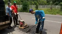 Petugas Dinas PU Bina Marga Cipta Karya Banyuwangi lakukan tambal sulam jalan berlubang (Hermawan Arifianto/liputan6.com)