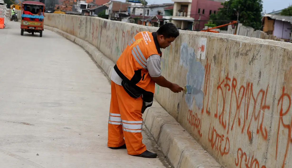 Petugas Pekerja Penanganan Sarana dan Prasarana Umum (PPSU) mengecat tembok yang penuh dengan vandalisme di sepanjang sisi tanggul Kali Ciliwung, Jakarta, Selasa (11/10). (Liputan6.com/Gempur M Surya)