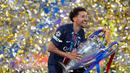 Kapten Paris Saint-Germain (PSG), Marquinhos, mengangkat trofi usai menjuarai Liga champions 2024/2025 di Stadion Allianz Arena, Minggu (01/06/2025) dini hari WIB. (AP Photo/Luca Bruno)