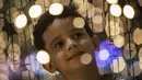 Seorang anak berpose di tengah lampu jelang perayaan Natal di sepanjang pantai Copacabana, di Rio de Janeiro, Brasil (11/12/2021). Jelang perayaan Natal, taman dan pantai dihiasi lampu-lampu yang indah. (AP Photo/Bruna Prado)