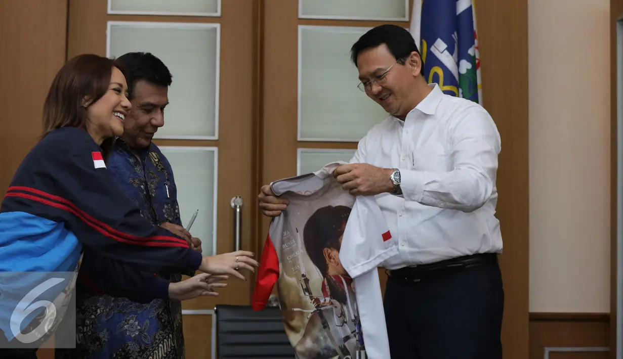 Gubernur DKI Jakarta Basuki Tjahaja Purnama menerima kaos film 3 Srikandi di Balai Kota, Jakarta, Selasa (19/7). Film 3 Srikandi melakukan promo sekaligus mengajak Ahok untuk nobar Film 3 Srikandi. (Liputan6.com/Herman Zakharia)