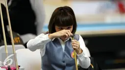 Pebiliar putri DKI Jakarta, Angeline M Ticoalu menggosok stik saat laga penyisihan 10 ball PON XIX Jabar di Graha Manggala Siliwangi, Bandung, Kamis (22/9). Angeline berhasil mengalahkan pebiliar Papua, Ari S Wati. (Liputan6.com/Helmi Fithriansyah)