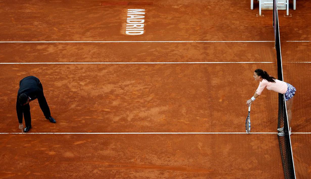 Petenis putri Polandia, Agnieszka Radwanska, melihat umpire yang menunjukkan bekas bola saat bertanding melawan petenis Slowakia, Dominika Cibulkova, dalam turnamen tenis Madrid Terbuka di Madrid, Spanyol, (1/5/2016). (Reuters/Susana Vera)