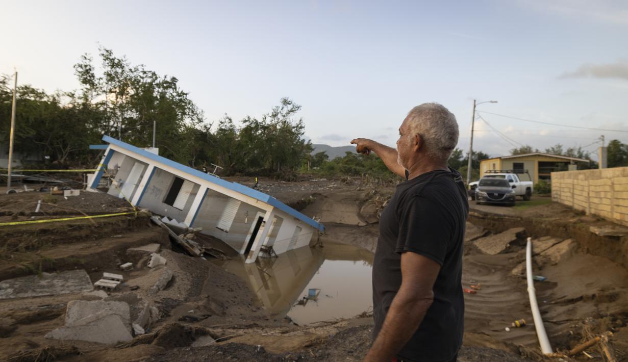 Seorang pria menunjuk ke sebuah rumah yang runtuh akibat Badai Fiona di Villa Esperanza di Salinas, Puerto Rico, Rabu, 21 September 2022. (AP Photo/Alejandro Granadillo)