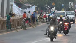 Warga membawa sapu menunggu pengguna jalan memberi sedekah dengan melempar uang di Jembatan Sewo, Jalur Pantura Sukra Indramayu, Jawa Barat, Senin (3/6/2019). Keberadaan pencari sedekah bisa membahayakan keselamatan pemudik serta pengguna jalan lainnya. (Liputan6.com/Herman Zakharia)
