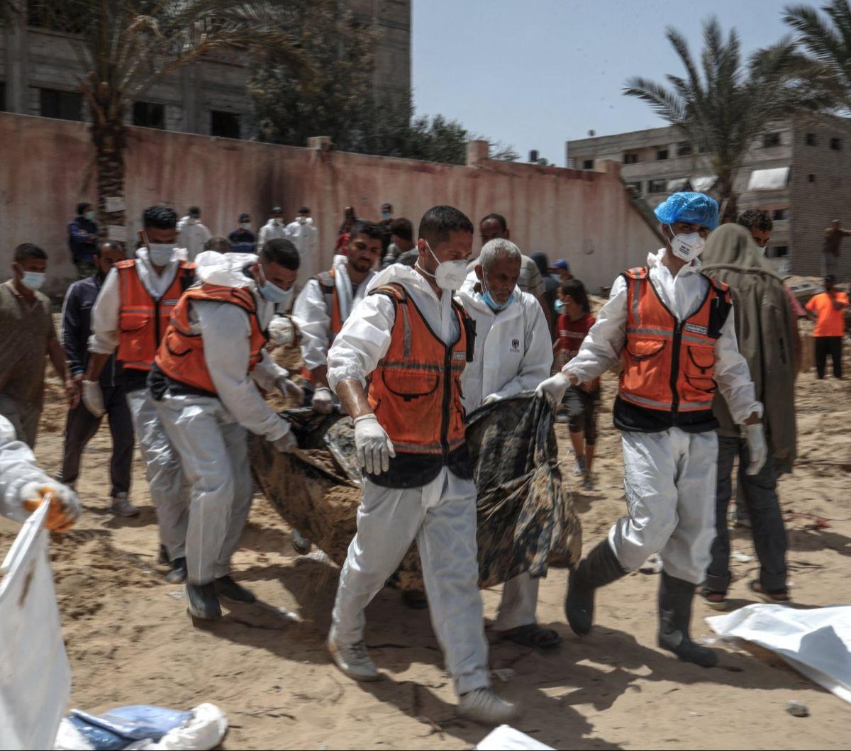 Sejumlah warga dan petugas kesehatan mengevakuasi jenazah di kuburan massal yang ditemukan di Rumah Sakit (RS) Al-Nasser, Jalur Gaza, Palestina, pada 23 April 2024. Kuburan massal dengan ratusan mayat ditemukan di dua rumah sakit Jalur Gaza yang sebelumn