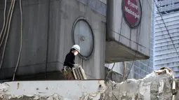 Pekerja membawa AC di lokasi pembongkaran Menara Kapsul Nakagin, bangunan ikonik yang dirancang arsitek Jepang Kisho Kurokawa pada tahun 1972, di distrik Ginza Tokyo, Selasa (12/4/2022). Pekerjaan pembongkaran menara 140 unit kapsul tersebut dimulai Selasa. (AP Photo/Eugene Hoshiko)