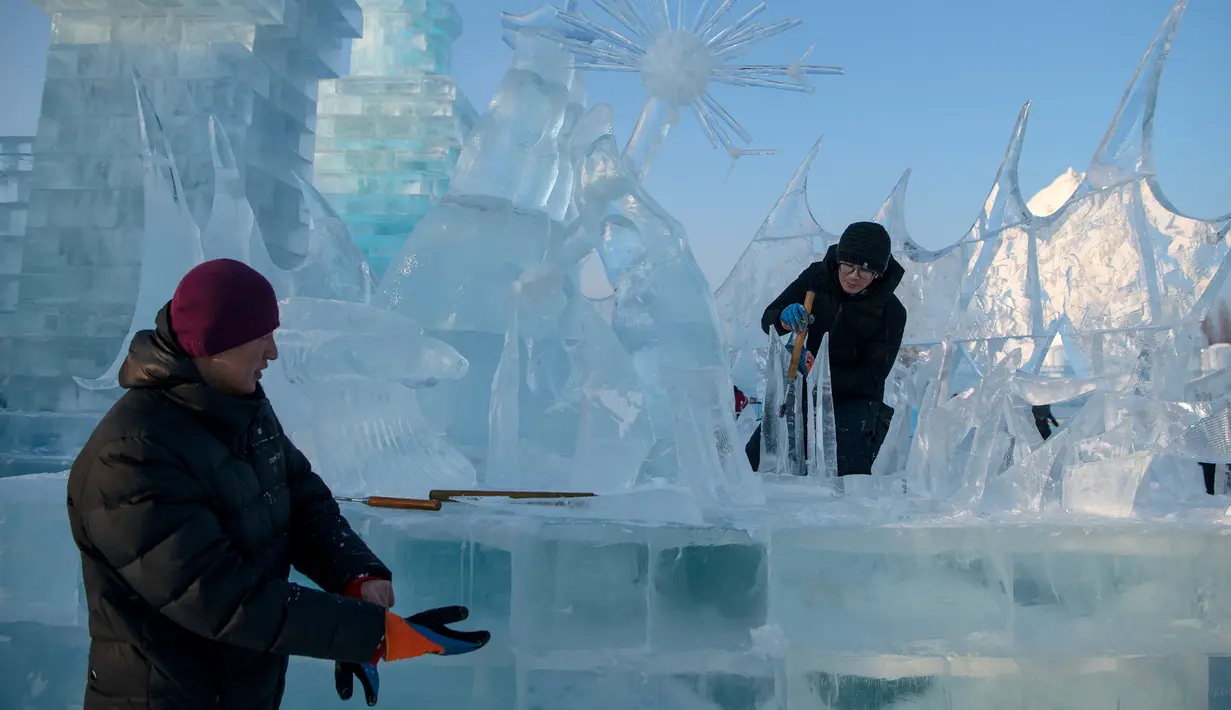 Pemahat es memberikan sentuhan akhir pada patung es di festival Ice and Snow World Harbin, di Harbin, timur laut China, Jumat (3/1/2019).  Festival es terbesar dunia tersebut diadakan untuk menyambut musim dingin yang berlangsung selama satu bulan lebih. (NOEL CELIS/AFP)