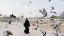 Mengabadikan foto bersama burung-burung di sekitaran Tanah Suci, Fuji terlihat mengenakan gamis dan hijab syar’i hitam. [Instagram/@fuji_an]