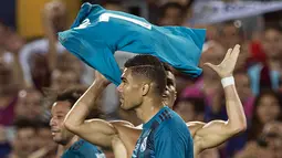 Pemain Real Madrid, Cristiano Ronaldo melepas dan mengangkat jerseynya di hadapan suporter Camp Nou pada leg pertama Piala Super Spanyol, Senin (14/8). Atas selebrasi berlebihan tersebut, Ronaldo pun mendapat kartu kuning dari wasit. (Josep LAGO/AFP)