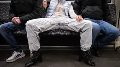 Elena Buscaino berpose dengan Riot Pants di antara dua pria di kereta bawah tanah di Berlin, 5 Februari 2021. Aktivis feminis Elena Buscaino dan Mina Bonakdar sedang dalam misi menghentikan kebiasaan penumpang pria melebarkan kaki saat duduk sehingga memakan dua kursi kereta. (STEFANIE LOOS/AFP)
