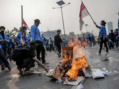Mahasiswa peserta aksi melakukan pembakaran sejumlah kardus saat menutup tol dalam kota di depan Gedung DPR/ MPR RI, Jakarta, Selasa (24/9/2019). Demonstrasi mahasiswa di depan Gedung DPR ini di antaranya menuntut penolakan atas pengesahan sejumlah RUU kontroversial. (Liputan6.com/Faizal Fanani)