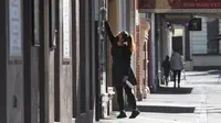 Seorang penjaga toko membersihkan jendela kafe di jalan yang sepi saat kota itu mengalami penguncian keenam saat memerangi wabah varian Delta dari coronavirus.di Melbourne (25/8/2021). (AFP/William West)